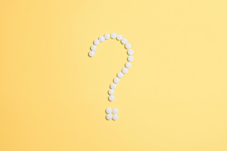 White pills arranged into a question mark shape on a vibrant yellow background.